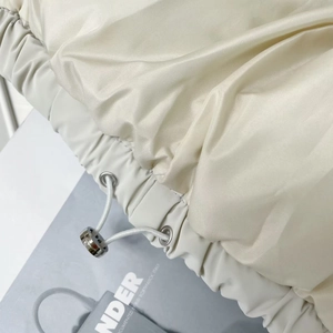 Detail of adjustable elastic drawstring with silver metal toggles on beige vest