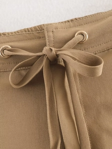 Macro detail of khaki pants waist featuring adjustable drawstring and golden metal eyelets