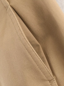 Detail of khaki twill cotton jacket side pocket with durable reinforced double-needle stitching