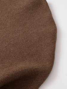 Detailed close-up of dark brown knit texture and fine craftsmanship on a poncho sweater