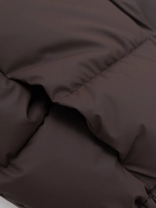 Close-up of quilted coffee brown puffer vest showing stitching and matte fabric texture