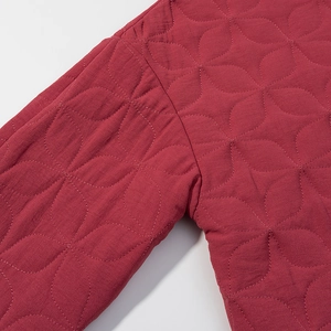 Detailed view of dark red quilted floral stitching on premium cotton jacket fabric