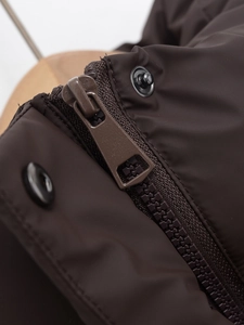 Close-up of resin zipper and matte metal snap button on dark brown winter vest