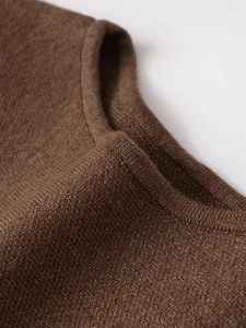 Detailed view of the crewneck collar and soft knit texture on this brown knit sweater