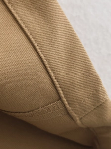 Close-up of khaki twill fabric detail showing refined stitching and textile texture