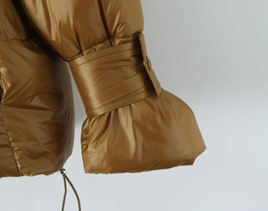 Close-up of caramel padded jacket sleeve with metallic finish and buckle detail