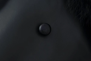 Detailed close-up of faux leather texture with matching button and black fur trim