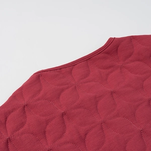Close-up of wine red quilted jacket featuring elegant floral stitching and round neck
