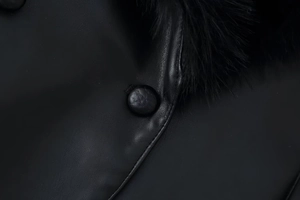 Detail of premium black leather jacket showing sewing craftsmanship and faux fur collar