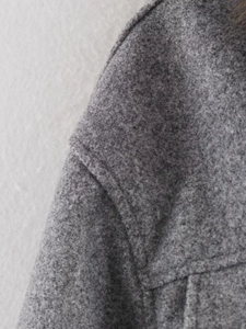 Macro detail of high-quality grey marl wool texture and fine shoulder stitching