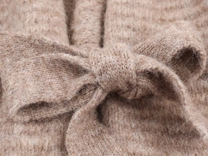Detailaufnahme der hellbraunen Strickjacke mit Pelztextur und Bindegürtel-Schleife