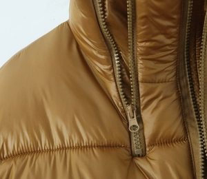Detail view of smooth metal zipper and stand collar on brown padded jacket