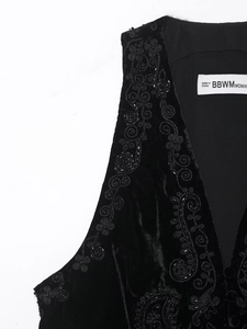 Détail de la broderie et des perles sur le gilet en velours noir montrant le tissu de luxe