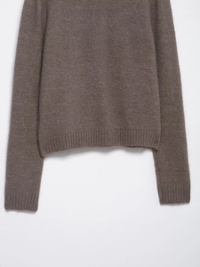 Macro detail of ribbed cuffs and faux fur texture on a tan knit cardigan sweater