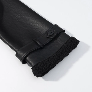 Detail view of faux leather coat cuff with black shearling lining and buckle strap