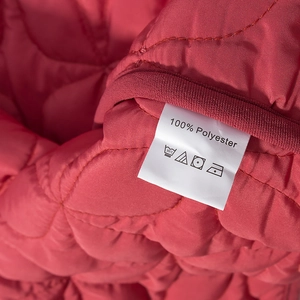 Macro view of 100% polyester fabric care label on red quilted winter jacket for women
