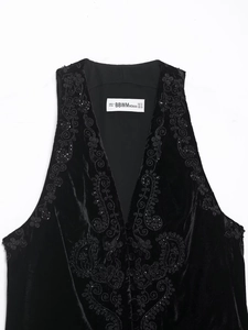 Détail de gilet en velours noir avec broderie complexe et ornements en perles noires