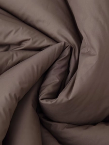 Macro shot of dark coffee puffer jacket fabric showing thick padding and matte texture