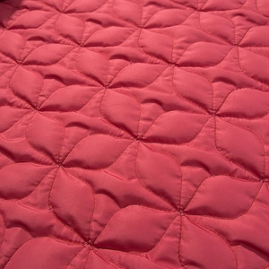 Macro detail of red quilted fabric with floral pattern and satin finish for winter coat