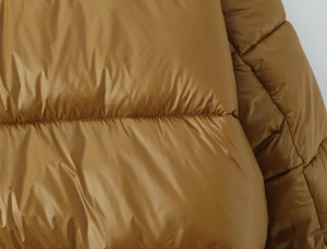 Close-up of glossy camel puffer jacket showing quilted fabric and padded texture