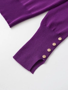 Detail of purple knit sweater cuff featuring elegant gold decorative buttons