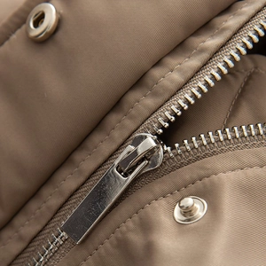Macro shot of silver metal zipper and snap buttons on khaki oversized pilot jacket