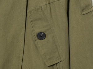 Détail d'un manteau en coton olive montrant le sergé et la poche à rabat boutonnée