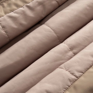 Macro detail of dusty pink quilted bomber jacket fabric with smooth glossy finish