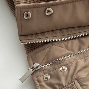 Detail of oversized bomber jacket showing metal zipper, buttons and ribbed collar texture