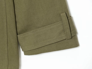 Détail du poignet de trench-coat en coton vert olive avec boucle de serrage ajustable