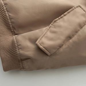Detail of khaki bomber jacket featuring ribbed knit cuffs and a pocket with flap cover