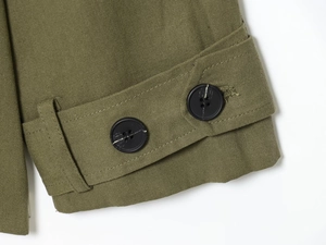 Détail de la manchette d'un trench en coton vert armée avec sangle et boutons noirs