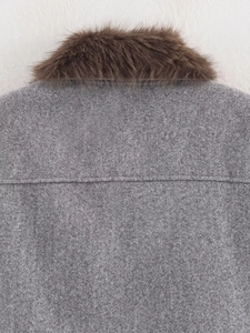 Detail of grey jacket featuring a plush brown faux fur collar and textured wool fabric