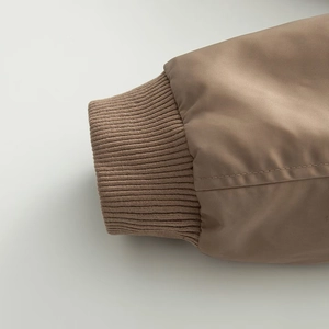 Detailed macro view of the brown bomber jacket's elastic ribbed cuffs and stitching