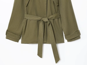 Détail d'un trench-coat vert armée avec ceinture à la taille et poignets ajustables