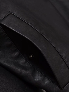 Close-up of black PU leather jacket pocket with silver metal snap button and fine stitching