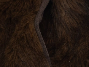 Macro shot of dark brown faux fur texture and neat stitched edge of the collar