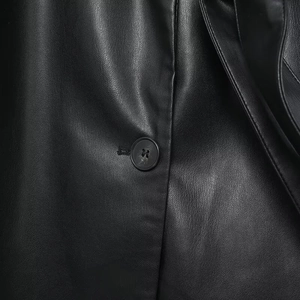 Close-up of black PU leather jacket showing grain texture and button stitching details