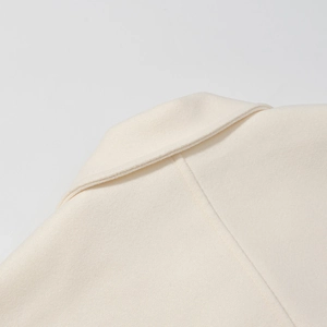 Details von Wollmischung-Revers und Nähten bei einem cremeweißen Modemantel