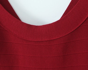 Detail view of the deep red ribbed knit fabric and circular neckline of the women's dress