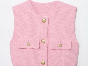 Close-up of pink tweed vest texture with elegant embossed gold buttons and flap pockets