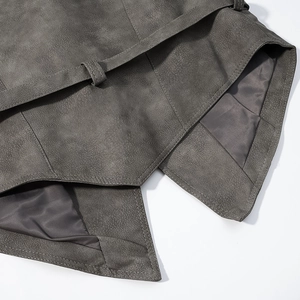 Détail macro de la veste en daim gris avec boucle de ceinture et doublure en soie