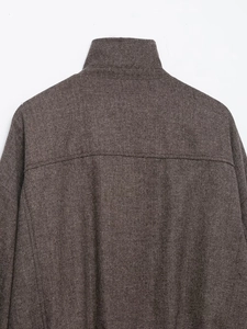 Close-up of herringbone weave texture on the collar and shoulder of the brown bomber jacket