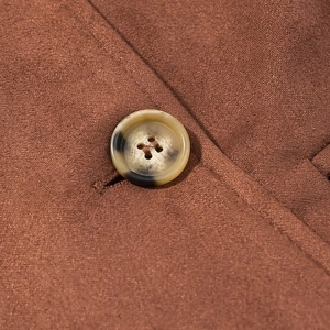 Gros plan d'un bouton marbré sur le trench-coat marron caramel en similicuir suédé