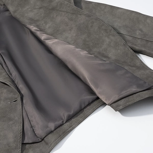 Détail de la veste grise en cuir PU avec coutures fines, texture daim et doublure lisse