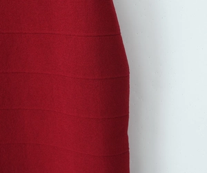 Close-up of deep red knit bandage dress showing elastic texture and horizontal weave detail