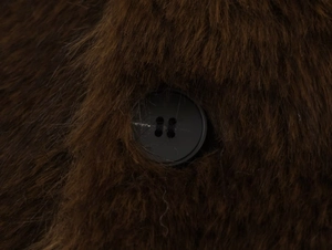 Gros plan détaillé sur la fourrure synthétique marron foncé avec bouton noir mat