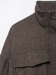 Macro shot of dark brown herringbone fabric texture and collar detail on bomber jacket