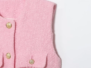 Close-up of pink tweed vest showing woven texture and gold embossed buttons detailing