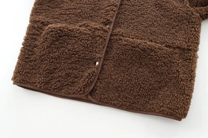 Détail de l'ourlet de la veste en polaire teddy marron avec deux poches plaquées